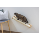 Eine Schildpattkatze, die auf einem wandmontierten Kratzbaum steht, mit einem grauen Kissen und einem Holzstuhl im Hintergrund.