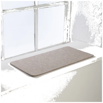 Eine weiche, beige Haustiermatte auf einer weißen Fensterbank, mit natürlichem Licht, das die Szene beleuchtet.