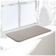 Eine weiche, beige Haustiermatte auf einer weißen Fensterbank, mit natürlichem Licht, das die Szene beleuchtet.