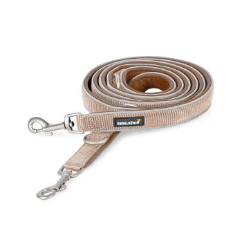 Eine aufgerollte beige Hundeleine mit einem silbernen Clip und einem schwarzen Etikett mit der Aufschrift 'RUDELKÖNIG.'