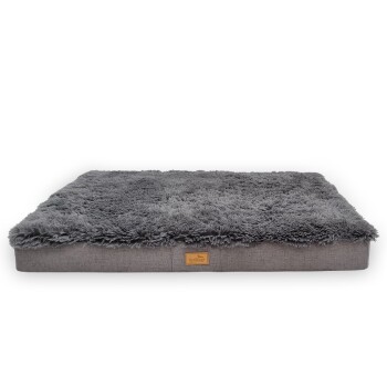 Graues Haustierbett mit einer plüschigen, zotteligen Oberseite und einem soliden grauen Boden, mit einem kleinen Lederschild mit dem Markennamen.