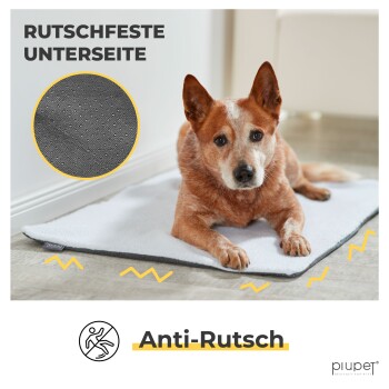 Ein braun-weißer Hund liegt auf einer weichen, grauen Haustiermatte mit rutschfester Unterseite, mit dem Text 'Anti-Rutsch' darüber.