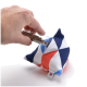 Eine Hand gießt getrocknete Kräuter aus einem Glasrohr in einen bunten, geometrisch gemusterten Stoffbeutel, der für Haustiere entworfen wurde.