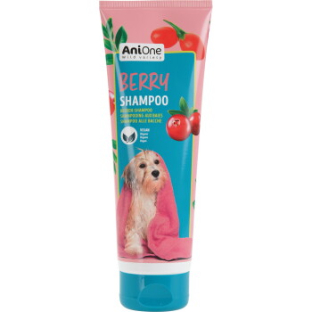 Tube de shampooing AniOne Wild Variety Berry avec canneberges, étiquette « VEGAN » et chien mouillé enveloppé dans une serviette rose.