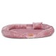 Ein plüschiges, rundes Haustierbett in sanftem Rosa mit einem kleinen passenden Kissen, mit einem Lederetikett, auf dem 'tierlando' steht.
