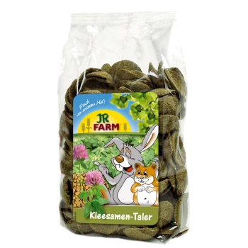 Eine durchsichtige Tüte mit grünen Haustierleckereien, beschriftet mit "Kleesamen-Taler" von JR FARM, mit einem glücklichen Hasen und Hamster auf der Verpackung.