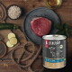 Dose LIEBESGUT Bio-Hundefutter mit der Aufschrift 'BIO-RIND' neben rohem Rindersteak, Zucchinischeiben, Haferflocken und Öl auf einem Holztisch.