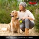 Eine Frau in einem gemütlichen Pullover und Beanie sitzt neben einem Golden Retriever auf einem sandigen Weg und hält eine flexi ausziehbare Hundeleine.
