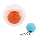 Interaktives Haustierspielzeugset mit einem klaren Ball mit einem orangefarbenen inneren Ball und einem blauen Ball, mit verstreuten Haustierleckereien in der Nähe.