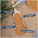 Holzlöffel gefüllt mit Samen auf Jute, beschriftet mit 'ausgewogen', 'energiespendend', 'artgerecht' und 'naturbelassen'.