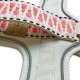 Nahaufnahme eines bunten Haustiergeschirrs mit einem pinken, goldenen und schwarzen gewebten Design, mit einem Lederetikett, das "HEY!" geprägt ist.