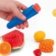 Eine Hand hält eine blaue Eisformen mit einem roten Eis am Stiel darin, umgeben von frischen Obstscheiben, darunter Wassermelone, Orange, Zitrone und Mango.