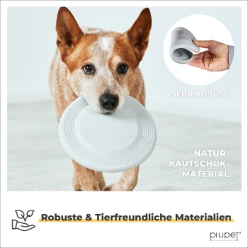 Ein Hund hält einen weißen Gummifrisbee im Mund und betont dessen Haltbarkeit mit "Sehr Robust" und "Natur-Kautschuk-Material."