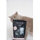 Eine graue Katze schaut neugierig über eine Tüte "CAT'S LOVE" Trockenfutter für Kätzchen, die Bilder eines schwarz-weißen Kätzchens auf der Verpackung zeigt.