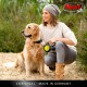 Une femme en pull et bonnet est assise avec un golden retriever sur un chemin sablonneux, tenant une laisse de chien flexi. Logo Flexi inclus.