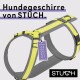 Ein graues und gelbes Hundegeschirr von STUCH, mit einem Etikett, das 'Vegan' liest und dem Text 'Hundegeschirre von STUCH.'