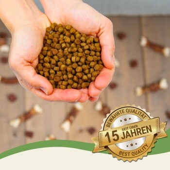 Zwei Schalen mit Trockenfutter (gelb und grün) mit weißen Seilspielzeugen. Text: "Glutenfrei," "Proteinreich," "Für Gelenke," "Vitamine A, E, D₃."