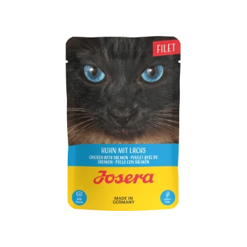 Nahaufnahme des Gesichts einer schwarzen Katze mit blauen Augen auf einem Hundefutterbeutel mit der Aufschrift "Huhn mit Lachs" und "Josera," mit "Getreidefrei"-Symbolen.