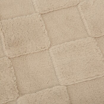 Nahaufnahme einer weichen beigen Haustierdecke mit einem karierten Muster aus plüschigen Quadraten.