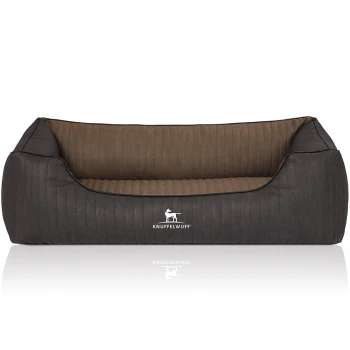 Orthopädisches Hundebett Outback aus laser-gestepptem Kunstleder schwarz/ gelb XL Ein stilvolles Hundebett mit einem dunkelgrauen Äußeren und einem weichen braunen Innenraum, das das Logo "KNUFFELWUFFF" auf der Vorderseite zeigt.