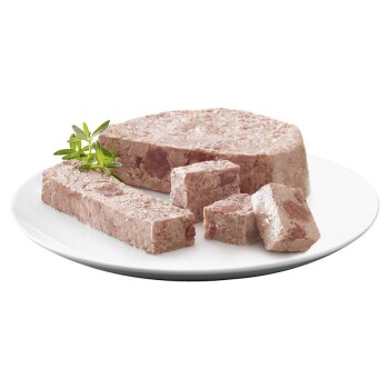 Ein Teller mit verschiedenen Stücken von Tierfutter-Pâté, einschließlich einer runden Scheibe und rechteckigen Stücken, garniert mit einem Zweig grüner Kräuter.