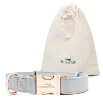 Hellgraues Haustierhalsband mit einer roségoldenen Schnalle, neben einem beigen Zugbeutel mit dem Logo "Freudentier" präsentiert.
