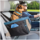 Ein kleiner brauner Hund sitzt sicher in einem Haustierautositz mit einem blauen Halsband, während eine Person fährt. Eine blaue zusammenklappbare Schüssel ist in der Tasche des Sitzes sichtbar.