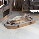 Eine entspannte cremefarbene und orangefarbene getigerte Katze liegt auf einem Kratzspielzeug mit Löchern, in einem gemütlichen Wohnzimmer nahe einem Kamin.