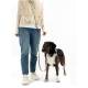 Person hält eine beige Hundeleine mit schwarzem Metallverschluss, trägt eine weiße Jacke und dunkle Jeans.