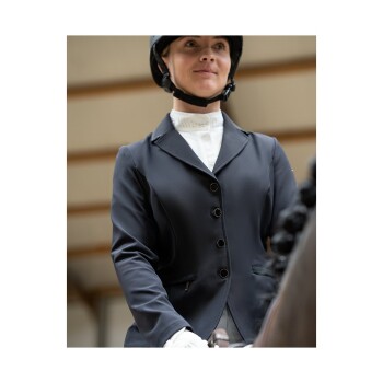 Ein Reiter in einer enganliegenden schwarzen Reitjacke und einem weißen Hemd, der einen Helm trägt, bereitet sich darauf vor, ein Pferd zu reiten.