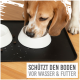 Ein Beagle frisst aus einer weißen Schüssel auf einer schwarzen Matte, mit Trockenfutter und Wassertropfen in der Nähe. Text: "SCHÜTZT DEN BODEN VOR WASSER & FUTTER."
