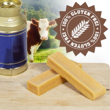 Zwei rechteckige Käsekaus für Hunde auf einer Holzoberfläche, mit einer blauen Milchkanne und einer Kuh im Hintergrund. Abzeichen liest "100% Glutenfrei."