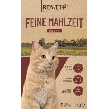 Nahaufnahme einer orangefarbenen Tabby-Katze auf einer Verpackung für Tiernahrung, beschriftet mit "Feine Mahlzeit Dreierlei" von REAVET, vor einer ländlichen Landschaft.