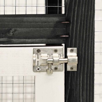 Nahaufnahme einer Holztür für Haustiergehege mit einem Metallverschluss und Drahtgeflecht, das den sicheren Verschlussmechanismus zeigt.