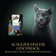 Eine graue Katze leckt sich die Lippen neben Sheba Nature's Collection Katzenfutter mit Thunfisch, Linsen, Karotten und Erbsen. Text: "AUSGEZEICHNETER GESCHMACK."