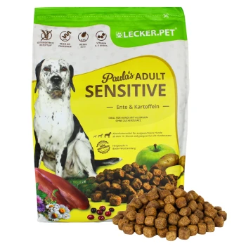 Hundefutterverpackung mit der Aufschrift "Paulo's ADULT SENSITIVE", die Ente und Kartoffeln enthält, mit Futterbrocken, die davor verstreut sind.