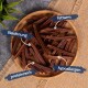 Eine Holzschüssel hält lange Hundeleckerlis, die auf Deutsch beschriftet sind: "Belohnung", "fettarm", "proteinreich" und "hypoallergen."