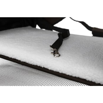 Nahaufnahme des Innenraums einer Transportbox für Haustiere mit einer weichen weißen Fleeceauskleidung und einem schwarzen Gurt mit einem Metallclip zur Sicherung der Haustiere.