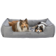 Zwei Hunde, ein rauhaariger Collie und ein kleiner schwarz-weißer Hund, entspannen zusammen in einem gemütlichen grauen Haustierbett mit der Aufschrift "homeEdition."
