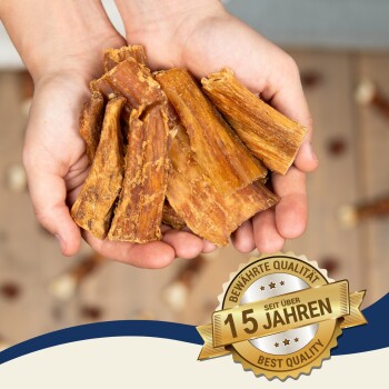 Ein Paar Hände hält mehrere Stücke Hundekauartikel, mit einem Abzeichen, das "15 Jahre" und "Beste Qualität" auf Deutsch angibt.