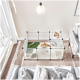 Ein transparenter Tierkäfig mit einem Kaninchen, das an einer Karotte knabbert, einer kleinen Katzenfigur und verschiedenen Spielzeugen auf Gras und Bettzeug.