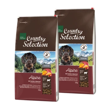 Zwei Säcke Real Nature Country Selection Hundefutter für Senioren, beschriftet mit "Alpen", mit einem Hund auf der Vorderseite und einem bergigen Hintergrund.