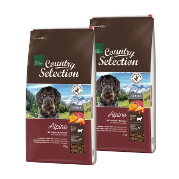 Dwie torby karmy dla psów Real Nature Country Selection dla seniorów, oznaczone 'Alpine', z psem na przodzie i górskim tłem.