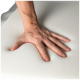 Eine Hand drückt in eine weiche, weiße Schaumoberfläche und hinterlässt einen Abdruck.