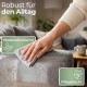Hand wischt mit einem Tuch über den Arm eines grauen Sofas, Wasser perlt ab; Text: 'Robust für den Alltag', 'Wasserabweisend', 'Pflegeleicht'.