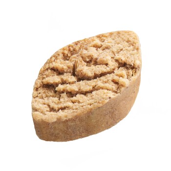 Ein strukturiertes, ovales Hundeleckerli in hellbrauner Farbe mit einer rauen Oberfläche, das einem Keks oder Keks ähnelt.