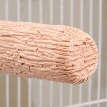 Nahaufnahme eines strukturierten, zylindrischen Terrakotta-Sitzstabs in einem weißen Metallhaustierkäfig.