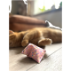Un chat orange endormi repose sur un sol en bois à côté d'un petit jouet rose avec des pois colorés.