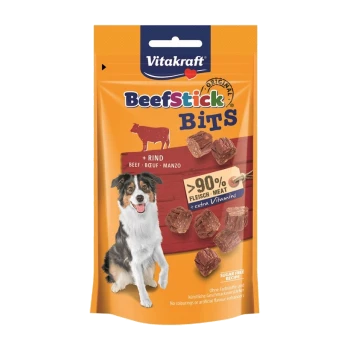 Vitakraft Beefstick Bits Hundeleckerlipackung mit einem glücklichen Hund, Stückchen von Rindfleischleckerlis und Text, der '>90% Fleisch' und 'extra Vitamine' hervorhebt.