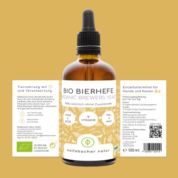 Eine Frau mit einer schwarzen Katze sitzt neben einem wolfähnlichen Hund in einem Garten mit lila Blumen. Text: "Als Tierheilerin liebe ich Wolfsbacher Naturprodukte."